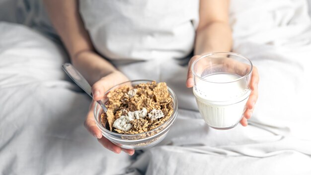 Primer plano de cereal y un vaso de leche en la cama