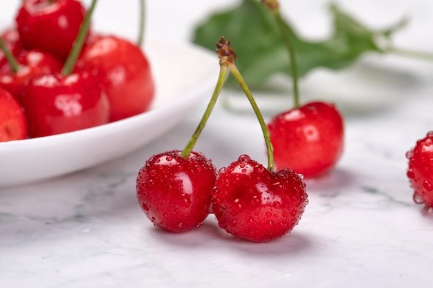 Primer plano de cerezas frescas en una mesa con un plato en el fondo borroso