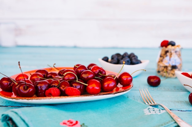 Foto gratuita primer plano de cerezas rojas frescas en un plato