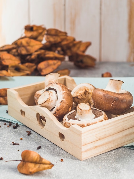 Primer plano de champiñones frescos en bandeja de madera