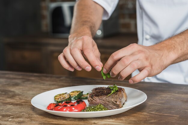 Primer plano del chef masculino decorar el plato