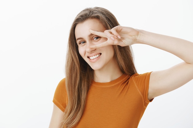 Primer plano de chica atractiva despreocupada con hermosa sonrisa que muestra gesto de paz