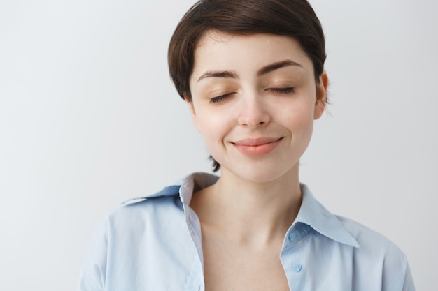 Primer plano de una chica atractiva soñadora cerrar los ojos y sonriendo, soñando despierto con algo agradable