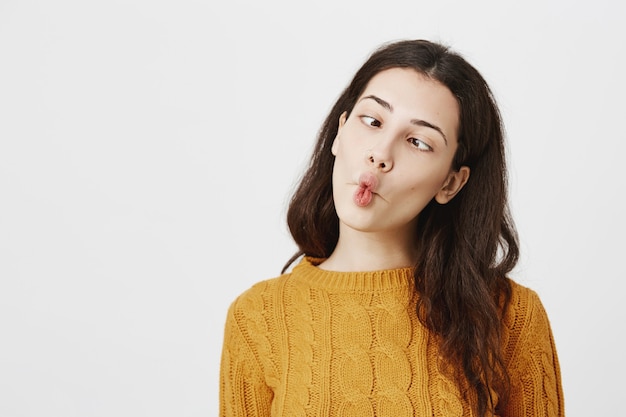 Primer plano de chica divertida divirtiéndose, entrecerrando los ojos y chupando los labios como peces