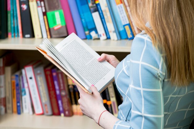 Primer plano de chica leyendo un libro en la biblioteca