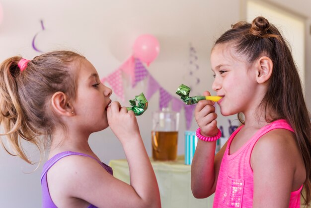 Primer plano de chicas lindas soplando cuerno fiesta disfrutando en fiesta