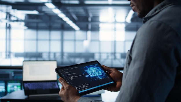 Un primer plano de un científico informático en un centro de datos utiliza la IA en una tableta
