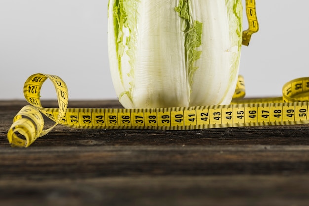 Foto gratuita primer plano de cinta métrica y lechuga en la superficie de madera