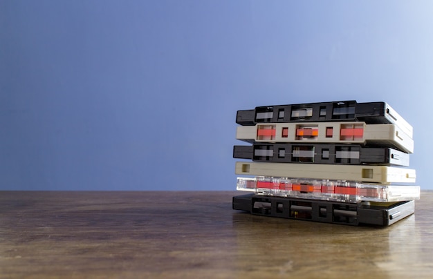 Primer plano de cintas de cassette en una mesa de madera con una pared azul