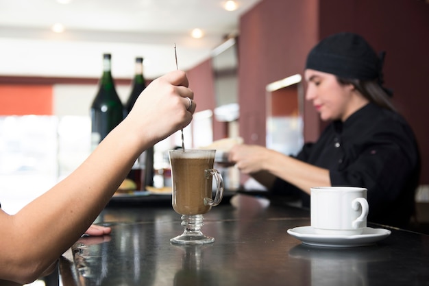 Primer plano del cliente en la barra de bar revolviendo cócteles en el bar