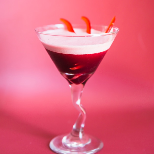 Primer plano de un cóctel fresco en vaso de martini sobre fondo rosa
