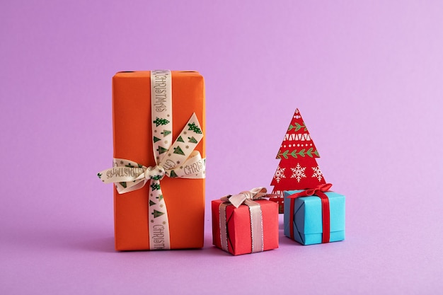 Primer plano de coloridas cajas de regalo y un árbol de Navidad de papel en el fondo púrpura