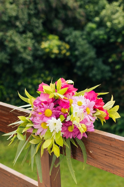 Primer plano de colorido ramo de flores atado en barandilla de madera en ceremonia de boda