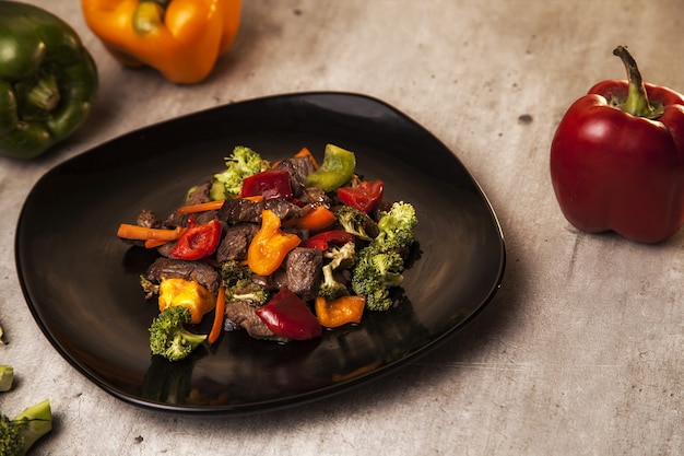 Primer plano de una comida deliciosa y saludable con carne y verduras asadas en una placa negra