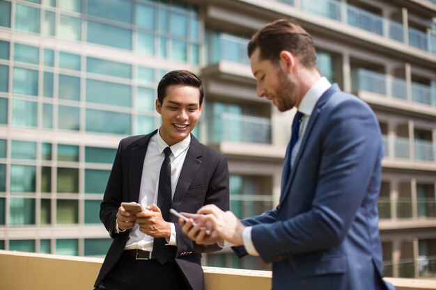 Primer plano de compañeros de trabajo Texting y charlando fuera