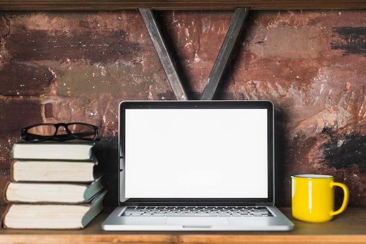 Foto gratuito primer plano de la computadora portátil; libros apilados; gafas y copa en estante de madera