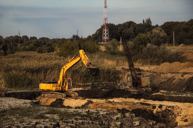 Primer plano de una construcción en curso con orugas y una excavadora en una tierra abandonada