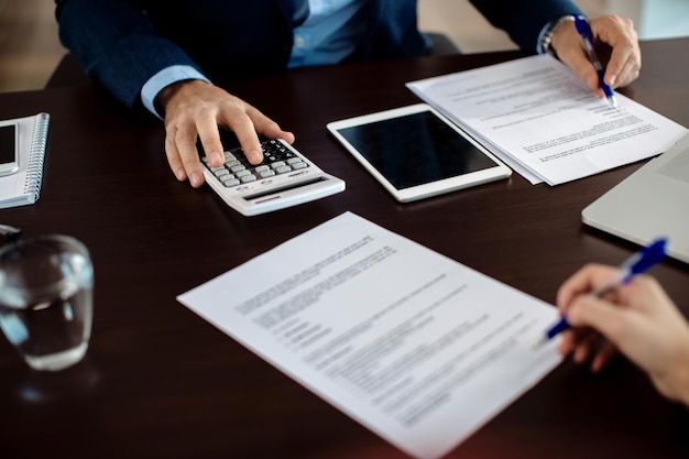 Primer plano de un consultor financiero revisando el papeleo en una reunión con un cliente