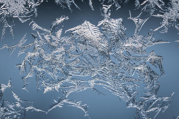 Primer plano de un copo de nieve en un vaso de escarcha, con patrón detallado