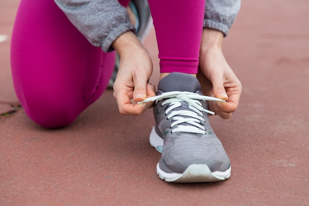 Primer plano del corredor que ata el cordón de zapato deportivo