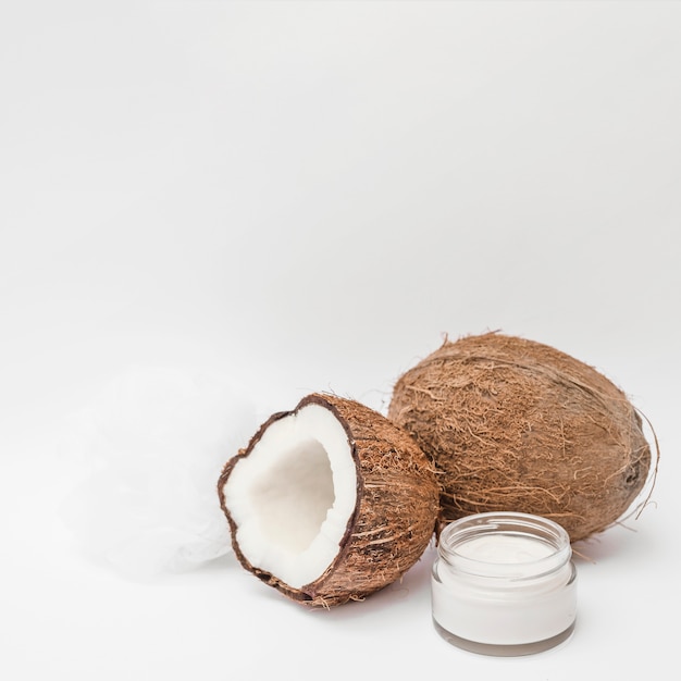 Primer plano de crema hidratante; Loofah y coco sobre fondo blanco