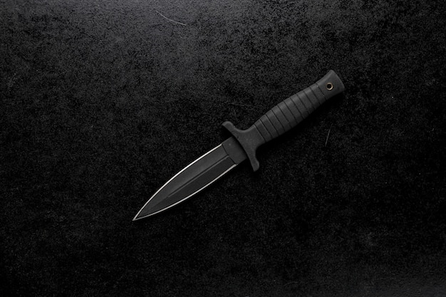 Primer plano de un cuchillo afilado fijo sobre un fondo negro