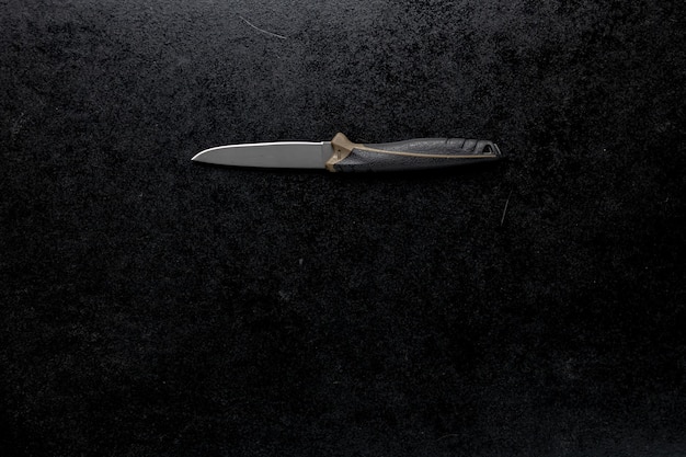 Primer plano de un cuchillo afilado fijo sobre una mesa negra