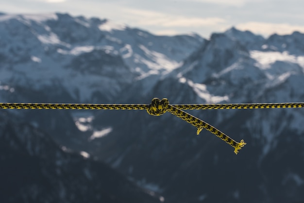 Foto gratuita primer plano de una cuerda torcida frente a las montañas cubiertas de nieve