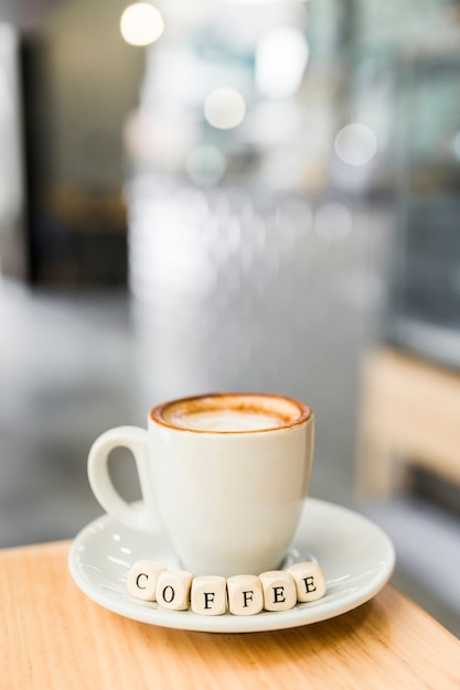 Foto gratuita primer plano de dados de café con taza de café en la mesa de madera