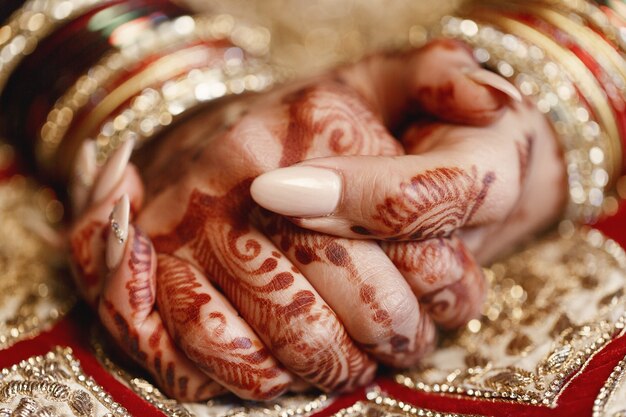 Primer plano de dedos largos de la novia cubiertos con mehndi y mentira