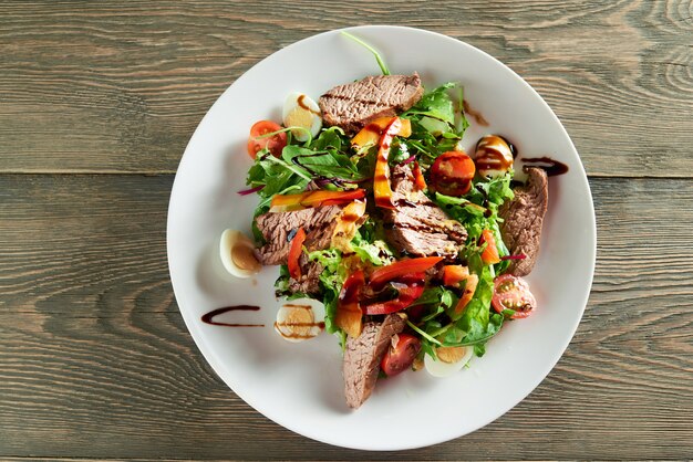 Primer plano de deliciosa ensalada de verduras, incluidas rodajas de ternera, huevos de codorniz, tomates cherry. Delicioso para comidas de restaurante con vino tinto claro o blanco o champán