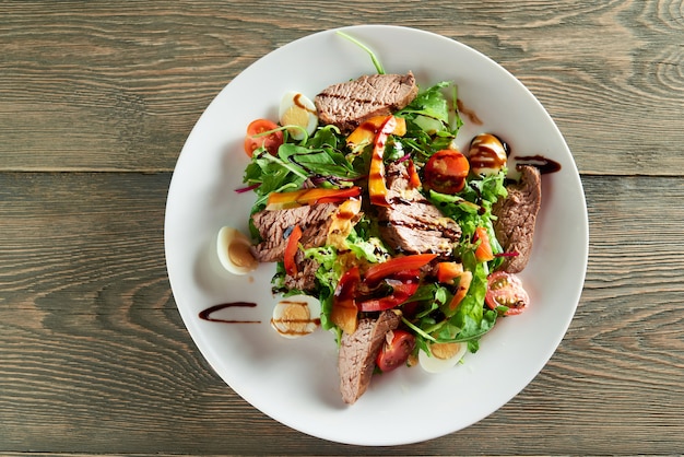 Primer plano de deliciosa ensalada de verduras, incluidas rodajas de ternera, huevos de codorniz, tomates cherry. Delicioso para comidas de restaurante con vino tinto claro o blanco o champán