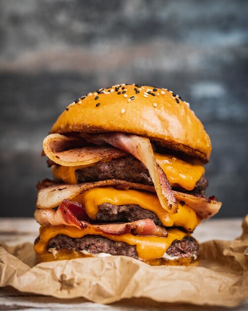 Primer plano de una deliciosa hamburguesa gigante con queso derretido de tocino frito y carne de res