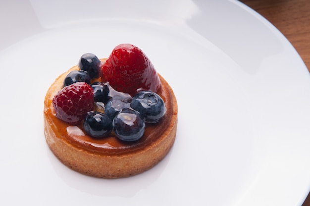 Primer plano de deliciosa mini tarta con bayas en placa