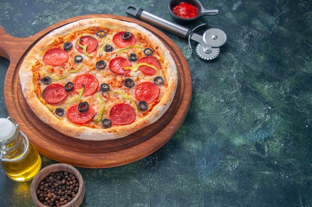 Primer plano de deliciosa pizza casera en tomates de tablero de madera y salsa de tomate de pimienta de botella de aceite en el lado derecho sobre una superficie oscura