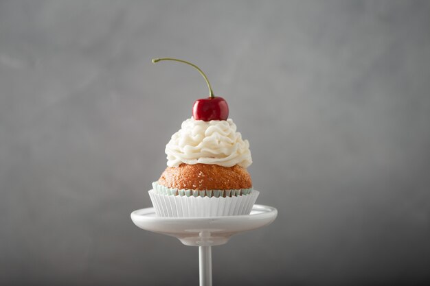 Primer plano de un delicioso cupcake con crema y cereza en la parte superior en un puesto de postres