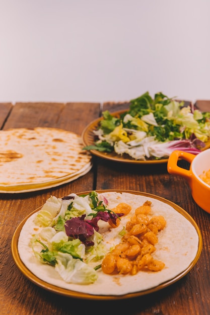 Primer plano de delicioso plato de maíz con verduras y tortilla en mesa marrón