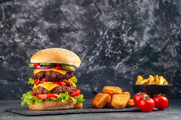 Primer plano de delicioso sándwich y nuggets de pollo ketchup en bandeja negra tomates sobre superficie de color oscuro