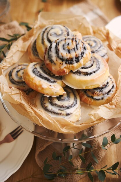 Primer plano de deliciosos pasteles de caracol amapola con un glaseado de azúcar sobre una mesa de madera