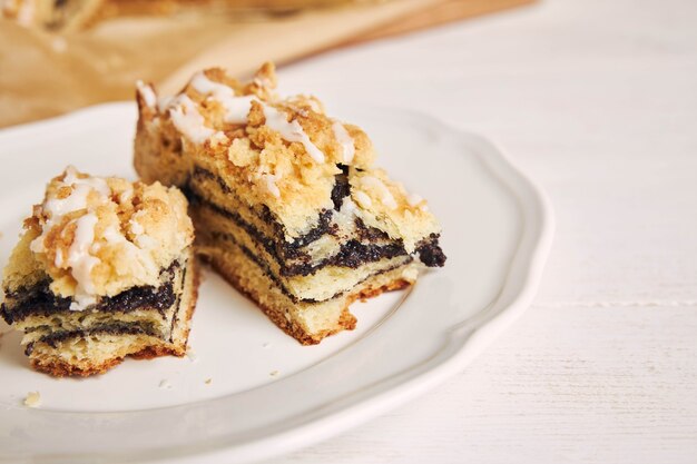 Primer plano de deliciosos trozos de pastel de semillas de amapola con un glaseado de azúcar blanco sobre una mesa blanca