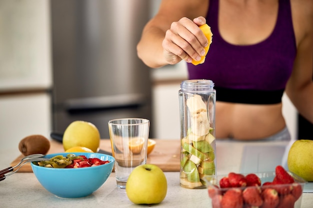 Foto gratuita primer plano de una deportista usando limón mientras hace un batido de frutas en casa