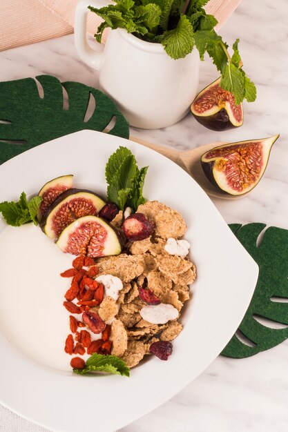 Primer plano de un desayuno saludable en un plato cerca de hojas falsas y una jarra de hojas de menta