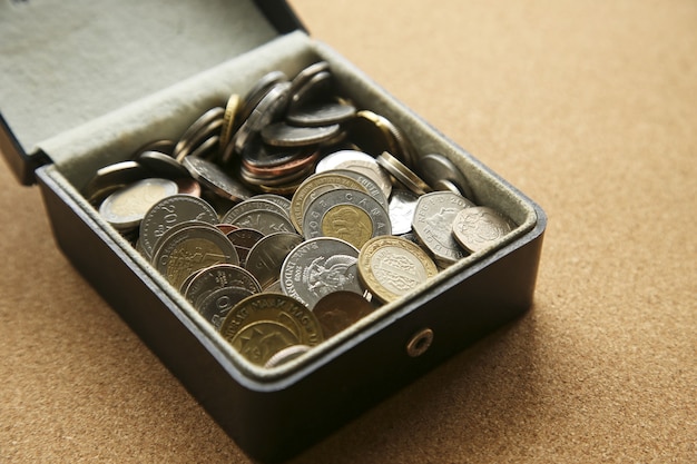 Primer plano de diferentes monedas en una caja sobre la mesa