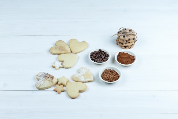Primer plano de diferentes tipos de galletas con granos de café, café instantáneo, cacao sobre fondo de tablero de madera blanca. horizontal