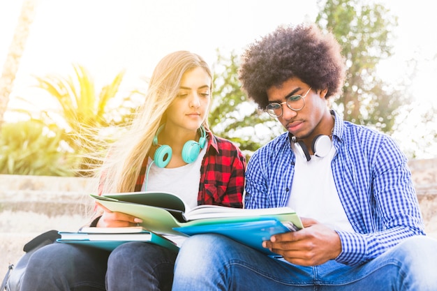 Primer plano de diversos jóvenes hombres y mujeres leyendo el libro