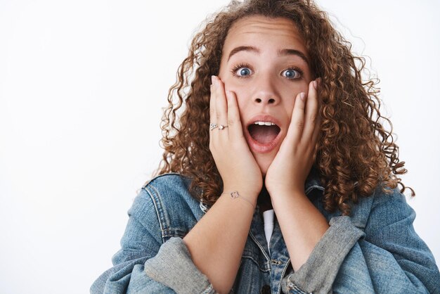 Foto gratuita primer plano divertido carismático linda mujer gordita de pelo rizado boca abierta sorprendido asombrado tocar las mejillas impresionado de pie sin palabras asombrado noticias impresionantes gritando mirada emotiva aturdida