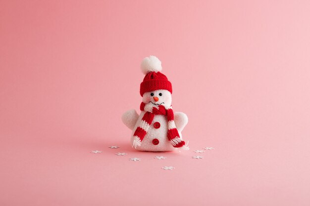 Primer plano de un divertido muñeco de nieve y copos de nieve en el fondo rosa