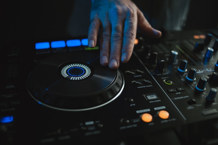 Foto gratuito primer plano de un dj trabajando bajo las luces de colores en un estudio con una borrosa