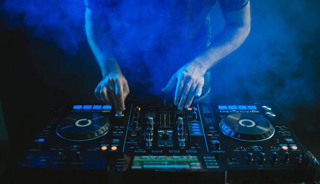 Primer plano de un DJ trabajando bajo la luz azul