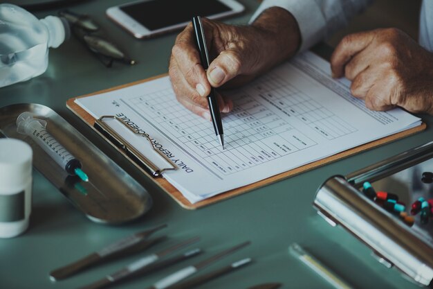Primer plano del doctor revisando la lista de verificación del informe diario del paciente